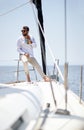 A young handsome male model at a photo shooting on a yacht on the seaside is enjoying a coffee and the sun. Summer, sea, vacation Royalty Free Stock Photo