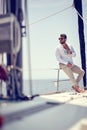 A young handsome male model is sitting on a yacht on the seaside and enjoying a photo shooting. Summer, sea, vacation Royalty Free Stock Photo