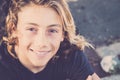 Young handsome male teenager in cheerful portrait with long blonde hair surf style - beautiful teen children looking on camera