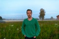 Young handsome man against grass field with fog in the break of dawn