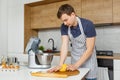 Young handsome man in apron kneading dough in modern kitchen. Concept of homemade bakery food, male cooking and domestic lifestyle Royalty Free Stock Photo