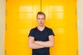 Young handsome man with arms crossed in front of yellow door Royalty Free Stock Photo