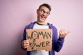 Young handsome man asking for women rights holding banner with woman power message pointing and showing with thumb up to the side Royalty Free Stock Photo