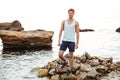 Young handsome man athlete standing at the rocky beach Royalty Free Stock Photo