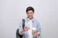 Young handsome man with backpack holding smart phone and coffee. Smiling student going on travel.  on white background Royalty Free Stock Photo