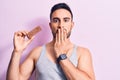 Young handsome man with beard eating energy protein bar over isolated pink background covering mouth with hand, shocked and afraid Royalty Free Stock Photo