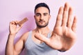 Young handsome man with beard eating energy protein bar over isolated pink background with open hand doing stop sign with serious Royalty Free Stock Photo