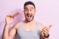 Young handsome man with beard eating energy protein bar over isolated pink background pointing thumb up to the side smiling happy Royalty Free Stock Photo