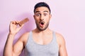 Young handsome man with beard eating energy protein bar over isolated pink background scared and amazed with open mouth for Royalty Free Stock Photo