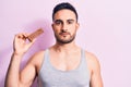 Young handsome man with beard eating energy protein bar over isolated pink background thinking attitude and sober expression Royalty Free Stock Photo