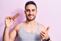 Young handsome man with beard eating energy protein bar over  pink background Smiling happy and positive, thumb up doing Royalty Free Stock Photo