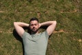 Young and handsome man, with a beard and green shirt, with his eyes closed and his hands behind the back of his neck lying on the Royalty Free Stock Photo