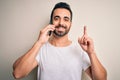 Young handsome man with beard having conversation talking on the smartphone surprised with an idea or question pointing finger Royalty Free Stock Photo