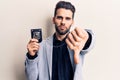 Young handsome man with beard holding police badge with angry face, negative sign showing dislike with thumbs down, rejection Royalty Free Stock Photo