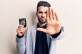 Young handsome man with beard holding police badge with open hand doing stop sign with serious and confident expression, defense Royalty Free Stock Photo