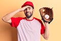Young handsome man with beard playing baseball using ball and glove stressed and frustrated with hand on head, surprised and angry Royalty Free Stock Photo