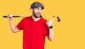 Young handsome man with beard playing golf holding club and ball pointing thumb up to the side smiling happy with open mouth Royalty Free Stock Photo