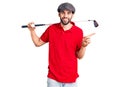 Young handsome man with beard playing golf holding club and ball smiling happy pointing with hand and finger to the side Royalty Free Stock Photo