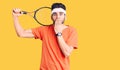 Young handsome man with beard playing tennis holding racket covering mouth with hand, shocked and afraid for mistake