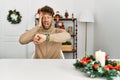 Young handsome man with beard sitting on the table by christmas decoration looking at the watch time worried, afraid of getting Royalty Free Stock Photo