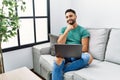 Young handsome man with beard using computer laptop sitting on the sofa at home looking confident at the camera smiling with Royalty Free Stock Photo