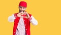 Young handsome man with beard wearing baseball jacket and cap smiling in love showing heart symbol and shape with hands Royalty Free Stock Photo