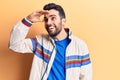 Young handsome man with beard wearing casual jacket very happy and smiling looking far away with hand over head Royalty Free Stock Photo