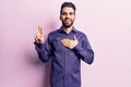 Young handsome man with beard wearing casual shirt smiling swearing with hand on chest and fingers up, making a loyalty promise Royalty Free Stock Photo