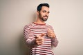Young handsome man with beard wearing casual striped t-shirt standing over white background pointing fingers to camera with happy Royalty Free Stock Photo