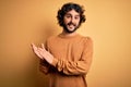 Young handsome man with beard wearing casual sweater standing over yellow background clapping and applauding happy and joyful, Royalty Free Stock Photo