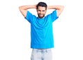 Young handsome man with beard wearing casual t-shirt relaxing and stretching, arms and hands behind head and neck smiling happy Royalty Free Stock Photo