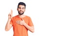 Young handsome man with beard wearing casual t-shirt smiling swearing with hand on chest and fingers up, making a loyalty promise Royalty Free Stock Photo