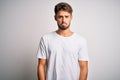 Young handsome man with beard wearing casual t-shirt standing over white background depressed and worry for distress, crying angry Royalty Free Stock Photo