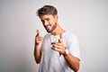 Young handsome man with beard wearing casual t-shirt standing over white background pointing fingers to camera with happy and Royalty Free Stock Photo