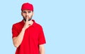 Young handsome man with beard wearing delivery uniform asking to be quiet with finger on lips