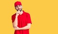 Young handsome man with beard wearing delivery uniform looking confident at the camera smiling with crossed arms and hand raised Royalty Free Stock Photo