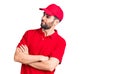 Young handsome man with beard wearing delivery uniform looking to the side with arms crossed convinced and confident Royalty Free Stock Photo