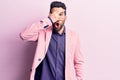 Young handsome man with beard wearing elegant jacket peeking in shock covering face and eyes with hand, looking through fingers Royalty Free Stock Photo