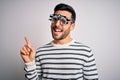 Young handsome man with beard wearing optometry glasses over isolated white background with a big smile on face, pointing with Royalty Free Stock Photo