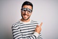 Young handsome man with beard wearing optometry glasses over isolated white background cheerful with a smile of face pointing with Royalty Free Stock Photo