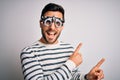Young handsome man with beard wearing optometry glasses over isolated white background smiling and looking at the camera pointing Royalty Free Stock Photo