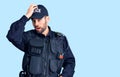 Young handsome man with beard wearing police uniform surprised with hand on head for mistake, remember error Royalty Free Stock Photo