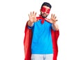 Young handsome man with beard wearing super hero costume afraid and terrified with fear expression stop gesture with hands, Royalty Free Stock Photo