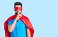 Young handsome man with beard wearing super hero costume asking to be quiet with finger on lips Royalty Free Stock Photo