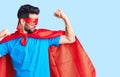 Young handsome man with beard wearing super hero costume showing arms muscles smiling proud Royalty Free Stock Photo