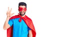 Young handsome man with beard wearing super hero costume showing and pointing up with fingers number three while smiling confident