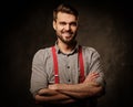 Young handsome man with beard wearing suspenders and posing on dark background. Royalty Free Stock Photo