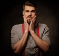 Young handsome man with beard wearing suspenders and posing on dark background. Royalty Free Stock Photo