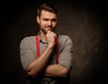 Young handsome man with beard wearing suspenders and posing on dark background. Royalty Free Stock Photo