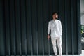 Young handsome man with beard and in white shirt is standing against dark green background Royalty Free Stock Photo